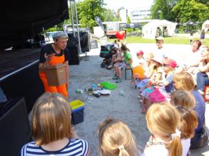Aufführung eines Theaterstücks vor einer Bühne: als Müllmann verkleideter "Herr Stinknich" interagiert mit Kindern