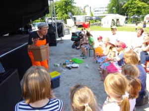 Aufführung eines Theaterstücks vor einer Bühne: als Müllmann verkleideter "Herr Stinknich" interagiert mit Kindern