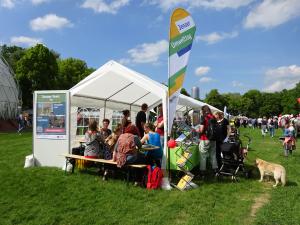 Weißer Pavillon auf einer Wiese mit Besuchern auf Bänken