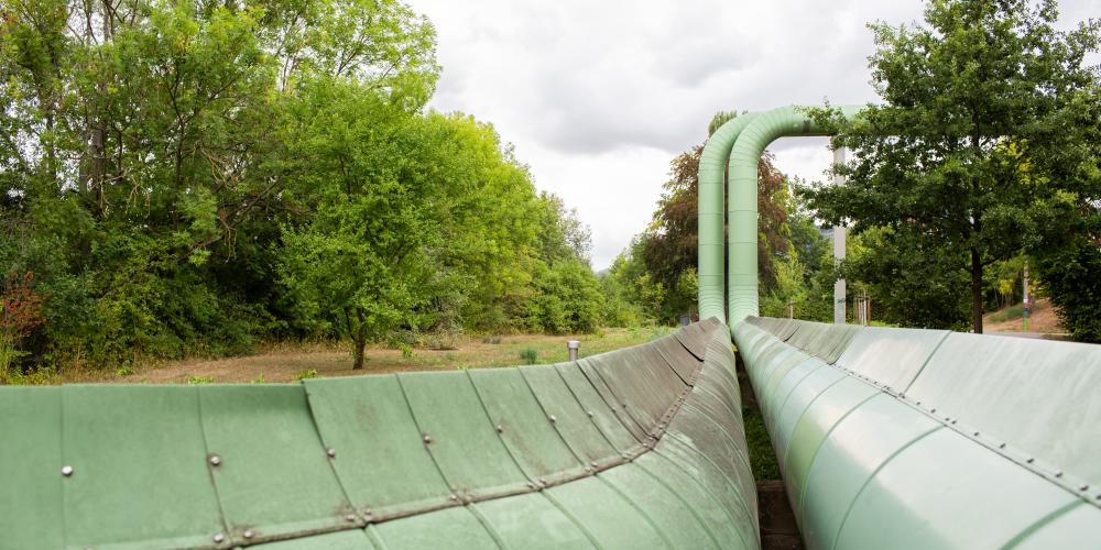 Grüne Fernwärmeleitungen in Jena, im Hintergrund Wiese und Bäume