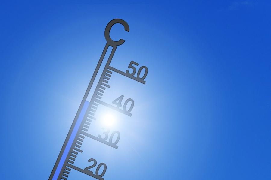Ein schwarzes Thermometer vor strahlend blauem Himmel, das 39 Grad Celsius anzeigt und das man gegen die Sonne betrachtet.
